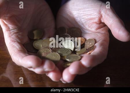 Faltige Hände älterer Frauen, die Münzen zählen Stockfoto