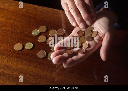 Faltige Hände älterer Frauen, die Münzen zählen Stockfoto