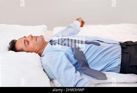 Absolute Erschöpfung. Ein Geschäftsmann lag völlig erschöpft auf seinem Bett. Stockfoto