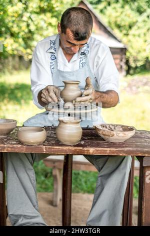 Sibiu City, Rumänien - 26 juli 2019. Hände eines Töpfers, der einen Tontopf auf einem Töpferrad auf der Töpfermesse aus Sibiu, Rumänien, formt Stockfoto