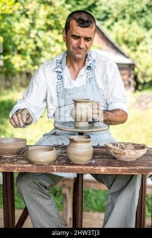 Sibiu City, Rumänien - 26 juli 2019. Hände eines Töpfers, der einen Tontopf auf einem Töpferrad auf der Töpfermesse aus Sibiu, Rumänien, formt Stockfoto