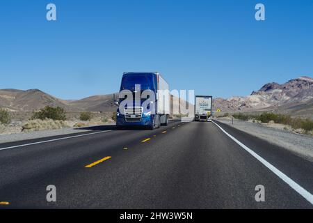 Nevada: Auf einem zweispurigen Highway in der Nähe der Stadt Beatty im Bundesstaat Nevada fahrende Sattelzüge. Stockfoto