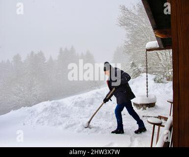 Schaufeln und Schneeräumung während eines Schneesturms im Gebiet Villars Sur Ollon in den Schweizer Alpen Stockfoto