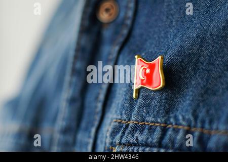 Das türkische Flag-Symbol ist an der blauen Jeansjacke festgezurtet. Konzept des Patriotismus der Türkei. Republikanischen Tag Urlaub in der Türkei. Stockfoto