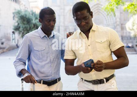 Fokussierte afroamerikanische Touristen, die per Telefon gehen Stockfoto