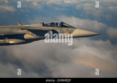 Ein schwedischer Saab JAS-39 Gripen-Kampfjet begleitet eine B-52H-Stratofortress, die während der Bomber Task Force England am 18. Februar 2022 dem Expeditionary Bomb Squadron 69., RAF Fairford, England, über Schweden zugewiesen wurde. Die schwedische Luftwaffe traf sich mit der B-52, um an Trainingsszenarien zur Stärkung der Interoperabilität zwischen den beiden Streitkräften zu arbeiten. (USA Air Force Foto von Tech. Sgt. Corban Lundborg) Stockfoto