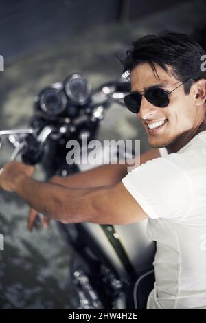 Bereit für die Straße. Ein hübscher junger Mann, der auf seinem Motorrad sitzt. Stockfoto