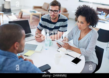 Teamdynamik. Aufnahme von Kollegen, die über ein digitales Tablet reden. Stockfoto