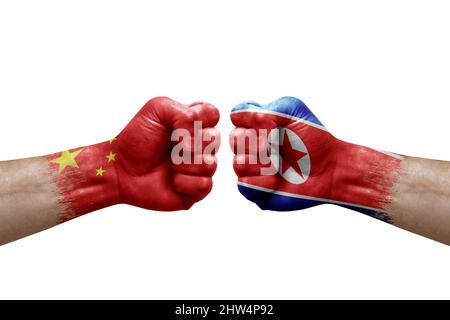 Zwei Hände schlagen sich gegenseitig auf weißem Hintergrund zu. Länderflaggen bemalten Fäuste, Konfliktkrisenkonzept zwischen china und Nordkorea Stockfoto