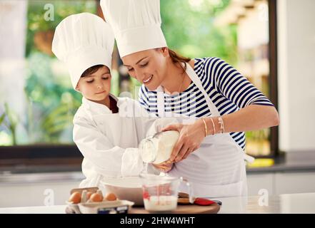 Ruhig bleiben und backen. Aufnahme einer Mutter und ihres Sohnes beim Backen in der Küche. Stockfoto