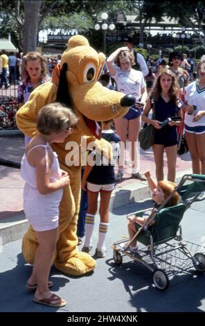 Besucher von Disneyland reagieren auf den kostümierten Charakter von Pluto Pup an der Main Street in Anaheim, CA Stockfoto