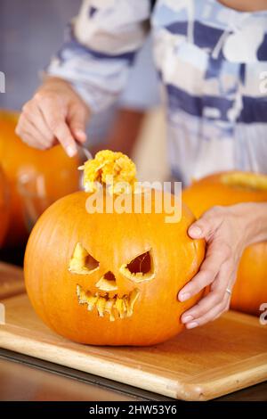 Warte, bis ich sie reinige Nahaufnahme einer Frau, die an Halloween eine Jack Olantern aushöhlen soll. Stockfoto