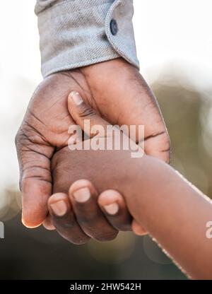 Ich werde euch durch das Leben führen. Nahaufnahme eines Vaters, der seine Söhne in der Hand hielt, während er im Freien zusammen ging. Stockfoto