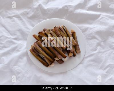 Platte mit rohen Rasiermuscheln auf einer weißen rauhen Papieroberfläche Stockfoto