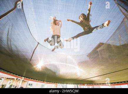Niedrige Ansicht der Schwestern (10-11, 12-13), die auf dem Trampolin springen Stockfoto