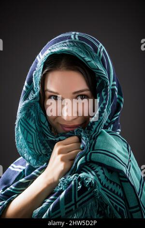 Studioporträt einer lächelnden Frau mit Schal auf dem Kopf Stockfoto