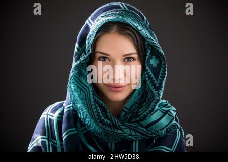 Studioporträt einer lächelnden Frau mit Schal auf dem Kopf Stockfoto