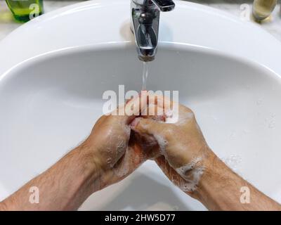 Die Person, die die Hände mit der Seife auf dem Badezimmer wascht Stockfoto