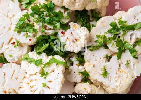 Rohe Blumenkohlscheiben mit Gewürzen bestreut. Kochen Blumenkohlesteak. Stockfoto