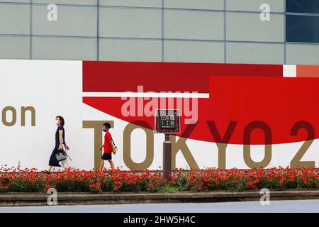 TOKIO, JAPAN - 30. Juli 2021: Menschen passieren einen Tokyo 2020-Designzaun vor einer Abrissstelle in Tokios Nihonbashi-Gegend. Stockfoto