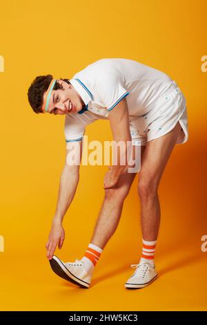 Strecke es aus. Ein Mann streckt seinen Wadenmuskel in Retro-Sportkleidung aus. Stockfoto