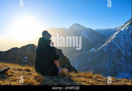 Mädchen sitzt im Winter auf einem Berg Stockfoto