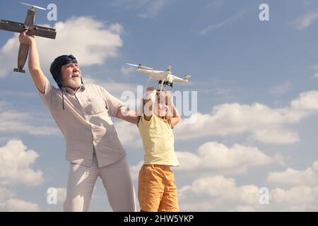 Großvater und Sohn halten Flugzeug und Drohne Quad Copter gegen den Himmel. Kind Pilot Flieger mit Flugzeug träumt vom Fliegen. Stockfoto