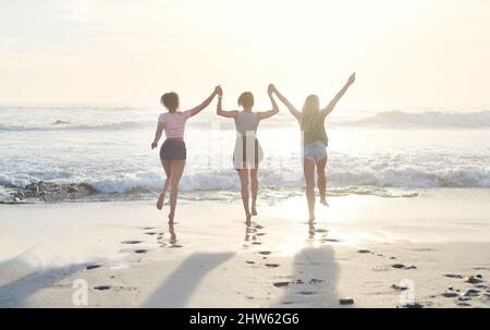 Es gibt keine bessere Möglichkeit, sich abzukühlen. Aufnahme von drei Freunden, die den Tag am Strand verbringen. Stockfoto