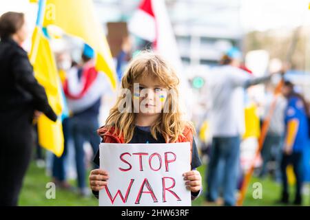 Porträt eines Jungen ruft den Krieg in der Ukraine zu stoppen und hält ein Plakat mit der Botschaft „Stoppt den Krieg“ im Freien. Russische Aggression. Kind trägt einen Stockfoto