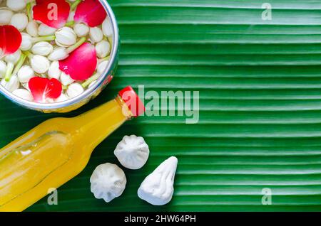 Songkran Festival Hintergrund mit Blumen in Wasserschale, duftendem Wasser und marmorhaltigem Kalkstein für Segen auf Bananenblatt Hintergrund. Stockfoto