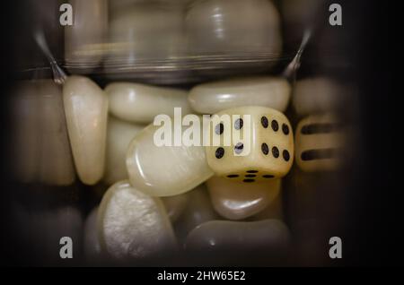 Weißer Iambic-Würfel aus Kunststoff in einer Glasflasche, umgeben von Kunststoffsteinen. Stockfoto
