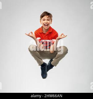 Glücklich lächelnder Junge, der in Yoga-Pose in der Luft fliegt Stockfoto