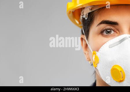 Arbeiterin oder Baumeisterin in Helm und Atemschutzmaske Stockfoto