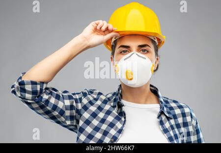 Arbeiterin oder Baumeisterin in Helm und Atemschutzmaske Stockfoto