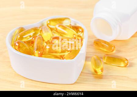 Cod Liver Oil Kapseln in weißer Tasse auf Holzfloor. Stockfoto