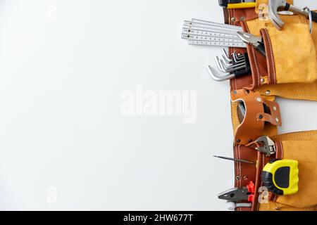Verschiedene Arbeitswerkzeuge im Gürtel auf weißem Hintergrund Stockfoto