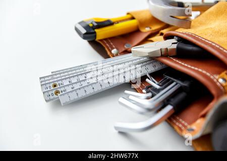 Verschiedene Arbeitswerkzeuge im Gürtel auf weißem Hintergrund Stockfoto