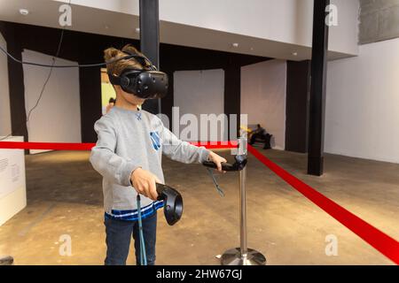 Acht Jahre Junge trägt VR-Headset, hält Controller in den Händen und genießen Sie neue Erfahrung in Videospielen. Spielstand auf der Messe der modernen tec Stockfoto