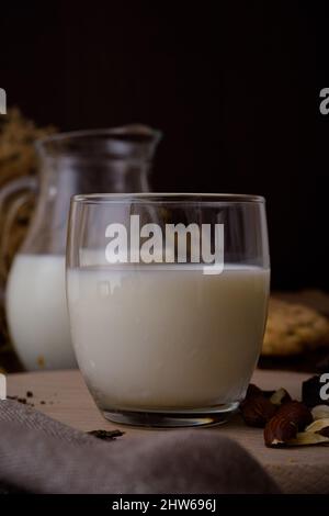 Vertikale Aufnahme von frischer Milch in Krug und Glas auf einem Holzbrett Stockfoto