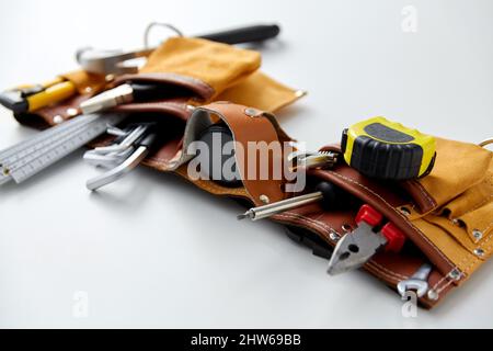 Verschiedene Arbeitswerkzeuge im Gürtel auf weißem Hintergrund Stockfoto