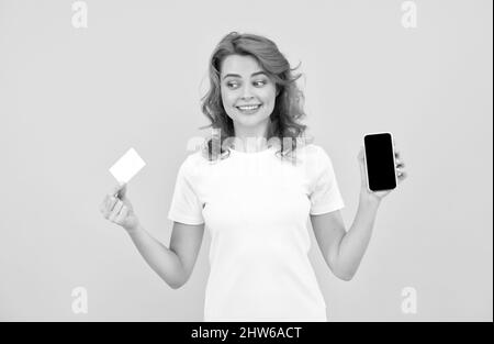 Glückliche Frau, die Kredit- oder Debitkarte und Smartphone zeigt, um online einkaufen zu können und online zu bezahlen. Stockfoto