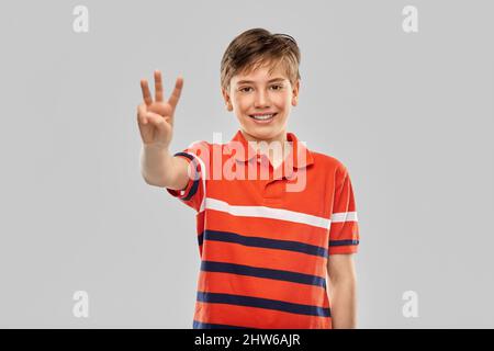 Porträt eines lächelnden Jungen, der drei Finger zeigt Stockfoto