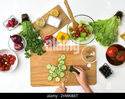 Hände schneiden Gurke auf Schneidebrett Stockfoto