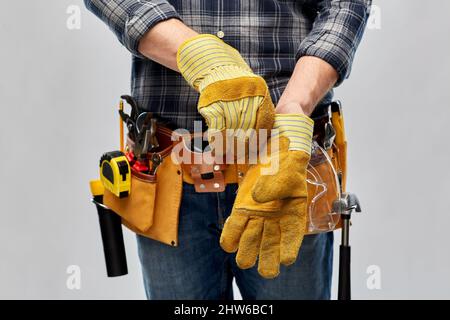 builder mit Arbeitswerkzeugen, die Handschuhe anziehen Stockfoto