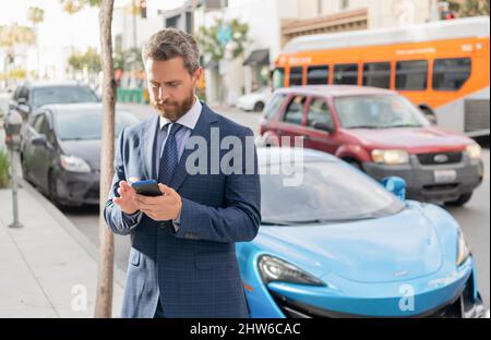 Autoversicherung. Geschäftsleute mieten ein Luxus-Auto per Telefon Stockfoto