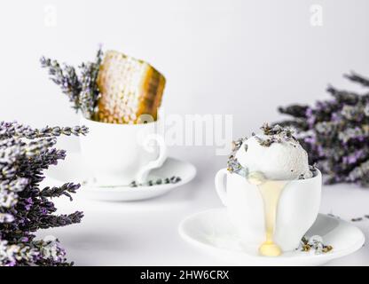 Eis in einer Kaffeetasse mit Lavendelblüten auf weißem Hintergrund Stockfoto