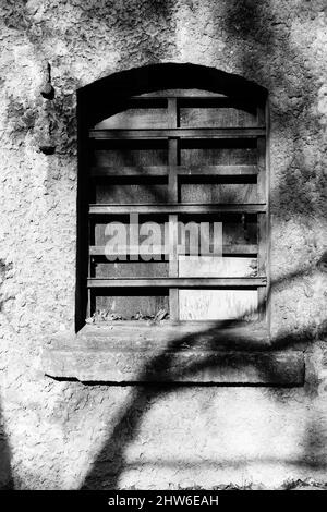 Vertikale Graustufenaufnahme eines Gebäudes mit einem Holzfenster Stockfoto