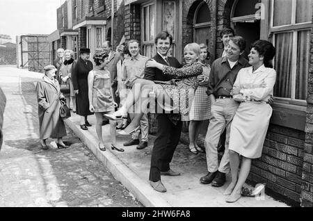 Eine neue Straßeneinstellung für die „Coronation Street“. Granada TV hat ein Outdoor-Set für einige der Szenen gebaut. Im Bild sind die Darsteller Dennis Tanner (Philip Lowrie) mit seiner Braut Jenny Sutton (Mitzi Rogers) nach ihrer Hochzeit mit Annie Walker (Doris Speed), Ena Sharples (Violet Carson), Emily Nugent (Eileen Derbyshire), Valerie Barlow (Anne Reid), Ken Barlow (William Roache) Len Fairclough (Peter Adamson) und Elsie Tanner (Pat Phoenix). 18. Mai 1968. Stockfoto