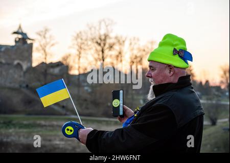 Dobele, Lettland - 2. März 2022: Ein Mann mit ukrainischer Flagge in den Händen geht zu einer Protestkundgebung gegen die russische Invasion in der Ukraine Stockfoto