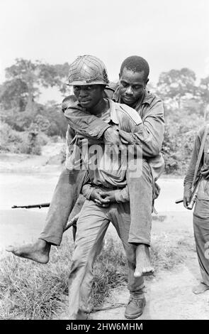 Ein biafranischer Soldat sah hier einen verletzten Kameraden während des Biafra-Konflikts tragen. 11.. Juni 1968 der nigeranische Bürgerkrieg, auch bekannt als Biafrankrieg, dauerte zweieinhalb Jahre, vom 6. Juli 1967 bis zum 15. Januar 1970, und wurde gekämpft, um der Abspaltung von Biafra von Nigeria entgegenzuwirken. Die indigenen Igbo-Bewohner von Biafra fühlten sich nach der Unabhängigkeit von Großbritannien nicht mehr mit der nordeuropäischen Bundesregierung koexistieren können. Politische, wirtschaftliche, ethnische, kulturelle und religiöse Spannungen kochten schließlich nach dem Militärputsch von 1966 in einen Bürgerkrieg über, dann in einen Gegenputsch, Stockfoto